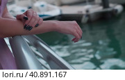 The hands of a young woman in a long purple dress lying on the handrails of a marina in Dubai. Стоковое видео, видеограф Aleksey Kidisyuk / Фотобанк Лори