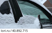 Person brushing fresh snow from car windows after snow storm blizzard. Morning routine difficulties of car owners in cold winter weather. Car window cleaning. Winter season. White snow. Vehicle care. Стоковое видео, видеограф Марина Демидюк / Фотобанк Лори