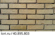 Yellow brick wall frontally. Ceramic brickwork or fence. Neatly and evenly laid brick. The light wall of the building, gray cement in the cracks. Sunny evening lighting. Стоковое фото, фотограф Юлия Петровская / Фотобанк Лори