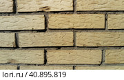 Yellow brick wall frontally. Ceramic brickwork or fence. Neatly and evenly laid brick. The light wall of the building, gray cement in the cracks. Sunny evening lighting. Стоковое фото, фотограф Юлия Петровская / Фотобанк Лори