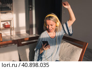 Happy middle aged woman wear earphones relax on couch listen to music on smartphone. Стоковое фото, фотограф Гладских Татьяна / Фотобанк Лори