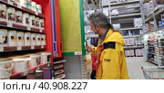 Buyer selects paint and plaster in the store (2018 год). Редакционное фото, фотограф Анна Кривицкая / Фотобанк Лори