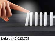 Woman hand toppling dominoes. Chain reaction business concept. Стоковое фото, фотограф Сергей Толмачёв / Фотобанк Лори