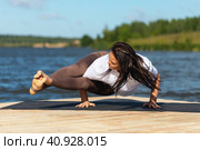 A woman practicing yoga, doing Ashtavakrasana exercise, balance asana, handstand, training in sportswear on the shore of the lake on a warm sunny morning. Стоковое фото, фотограф Сергей Чайко / Фотобанк Лори