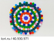 Multi-colored polypropylene caps are laid out on the table in the form of a round flower. Children collect plastic waste to be recycled. The concept of separate waste collection. Flat lay, close-up, mock up. Стоковое фото, фотограф Виктория Катьянова / Фотобанк Лори