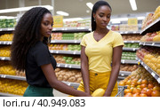 Attractive young black woman working in a supermarket, wearing a yellow shirt and dark trousers. Black Women owning small business posing looking at the camera with hand crossed. Business concept. Стоковая иллюстрация, иллюстратор Sergey Grishin / Фотобанк Лори