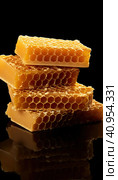 Golden wax honeycombs with honey lie on a shiny black background. Created by AI. Стоковое AI-изображение, AI-художник Ярославский Максим / Фотобанк Лори