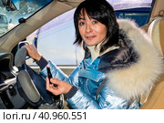 Young woman driving the car and make up lips with lipstick. She smiling mysteriously and looking at the camera. Стоковое фото, фотограф Татьяна Терехина / Фотобанк Лори
