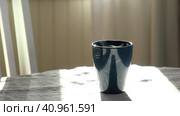 Steaming Cup of Coffee or Tea on Table. White linen Tablecloth. Close-up ceramic blue mug with smoke on old table in dining room interior background. Hot Drink Concept. Cozy Morning. Стоковое видео, видеограф Марина Демидюк / Фотобанк Лори