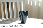 Steaming Cup of Coffee or Tea on Table. White linen Tablecloth. Close-up ceramic blue mug with smoke on old table in dining room interior background. Hot Drink Concept. Cozy Morning. Стоковое видео, видеограф Марина Демидюк / Фотобанк Лори