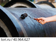 Construction roller in the man's hand. The process of painting reinforced concrete sewer pipes with bitumen. Waterproofing in cold and hot way. Construction technologies. Стоковое фото, фотограф Алексей Игнатов / Фотобанк Лори