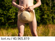Crop photo of naked shy man nudist covering summer hat on greenery nature outdoors, close up. Confused nude young male standing, natural idyllic lifestyle. Nudism naturism concept. Copy ad text space. Стоковое фото, фотограф Aleksandr Golubev / Фотобанк Лори