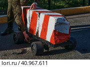 Road checkpoint. The soldier moves the barrier. Control of the movement of vehicles during a special operation. Special device on the road. The mobile block on wheels for the pass of cars. Стоковое фото, фотограф Алексей Игнатов / Фотобанк Лори