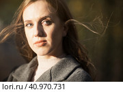 Портрет красивой молодой женщины со светло-каштановыми волосами. Привлекательная девушка в сером пальто смотрит в сторону. Грустное или мечтательное осеннее настроение. Лицо крупным планом. Волосы развеваются на ветру. Стоковое фото, фотограф Андрей Степанов / Фотобанк Лори