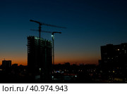 Строящийся жилой дом и строительные краны на закате. Лето. Москва (2023 год). Редакционное фото, фотограф E. O. / Фотобанк Лори
