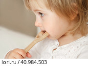 Cute baby girl playing tactile wooden and silicone toys. Young child hand plays sensory massage ball. Enhance the cognitive, physical process. Brain development. Teething toy. Dentition. Baby's teeth. Стоковое фото, фотограф Марина Демидюк / Фотобанк Лори