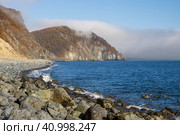 Красивый морской пейзаж. Вид на морское побережье и мыс. Низкие облака и туман над морем. Осенний сезон. На скалистом берегу никого нет. Побережье Охотского моря, Магаданская область, Дальний Восток России. Стоковое фото, фотограф Андрей Степанов / Фотобанк Лори