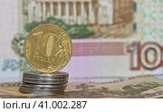 Деньги. Монета номиналом в 10 рублей на стопке монеток в 1 рубль на фоне 100-рублевых купюр. Стоковое фото, фотограф E. O. / Фотобанк Лори
