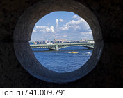 Вид на Троицкий мост через круглое окошко в башенке на крыше Государева бастиона Петропавловской крепости. Санкт-Петербуг, солнечный летний день. (2023 год). Стоковое фото, фотограф Сергей Рыбин / Фотобанк Лори