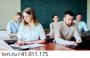 Asian woman and caucasian man university students sitting at table during lesson and using laptop. Стоковое видео, видеограф Яков Филимонов / Фотобанк Лори