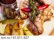 Grilled chicken, baked with potatoes and chili pepper. Food is served on a platter with tomato sauce and decorated with rosemary branch. Курица-гриль, запеченная с картофелем и перцем чили. Блюдо подается на блюде с томатным соусом и украшается веточкой розмарина. Стоковое фото, фотограф Дмитрий Березнев / Фотобанк Лори