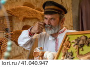 Продавец сувенирной продукции на фестивале "Русское поле" в парке Коломенское города Москвы, Россия (2023 год). Редакционное фото, фотограф Николай Винокуров / Фотобанк Лори