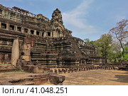 Ancient stone temple of Baphuon in Angkor. A dilapidated building in the shape of a stepped pyramid. Empty window openings are visible. At the top - a tower, colonnades. Blue sky, sunny day. Cambodia (2019 год). Стоковое фото, фотограф Вера Ивановна Кубарева / Фотобанк Лори