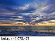 Colorful sunset over the Black Sea. The sun disappeared. There are purple clouds in the blue sky. An orange glow above the horizon. Shadows and highlights on the water. Waves foaming on a pebble beach. Стоковое фото, фотограф Вера Ивановна Кубарева / Фотобанк Лори