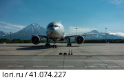 The plane is standing on the landing strip of the airfield. Behind him are picturesque snow-capped volcanoes against a clear blue sky. Petropavlovsk Kamchatsky. Стоковое фото, фотограф Вера Ивановна Кубарева / Фотобанк Лори