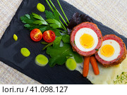 Dish scotch egg with tomatoes, mashed potatoes and greens, traditional Scottish cuisine. Стоковое фото, фотограф Яков Филимонов / Фотобанк Лори
