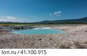 In the caldera of an extinct volcano there is a turquoise translucent lake from hot springs. There are sulphurous deposits on the rocky soil around. Mountains against the blue sky. Kamchatka. Uzon. Стоковое фото, фотограф Вера Ивановна Кубарева / Фотобанк Лори