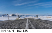 The highway passes through a snowy valley. A white dividing line is visible in the middle. On the roadsides there are figures of idols. Ahead is a blue sky, a mountain range. Altai. Стоковое фото, фотограф Вера Ивановна Кубарева / Фотобанк Лори