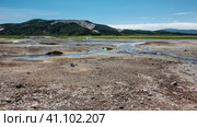 Blue streams from hot springs are visible in the caldera of an extinct volcano. There are sulphurous deposits on the soil. A picturesque mountain range against the azure sky. Kamchatka. Uzon. Стоковое фото, фотограф Вера Ивановна Кубарева / Фотобанк Лори