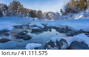 An ice-free river flows between snowdrifts. Fluffy frost on the stones. Steam over the water. Mountain range and coniferous forest against the blue sky. Altai. Katun. Стоковое фото, фотограф Вера Ивановна Кубарева / Фотобанк Лори