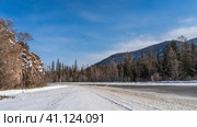 The highway goes around a cliff with steep slopes. Trees grow in snowdrifts on the roadsides. A mountain range against the blue sky. Altai. Chuysky tract. Стоковое фото, фотограф Вера Ивановна Кубарева / Фотобанк Лори