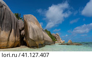 Amazing beach on a tropical island. Boulders in the turquoise ocean. On the shore there are huge granite rocks with smoothed steep slopes. Blue sky, clouds. Seychelles. La Digue. Anse Source D’Argent. Стоковое фото, фотограф Вера Ивановна Кубарева / Фотобанк Лори