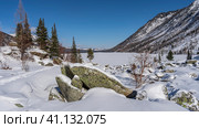 In the valley, under a layer of snow, there are picturesque boulders. A chain of footprints trampled through snowdrifts leads to a frozen lake with a snow-covered untouched surface. Altai. Стоковое фото, фотограф Вера Ивановна Кубарева / Фотобанк Лори