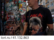 Мужчина в футболке с портретом лидера рок-группы "Алиса" Константина Евгеньевича Кинчева у стены Виктора Цоя на улице Арбат в центре города Москвы, Россия (2023 год). Редакционное фото, фотограф Николай Винокуров / Фотобанк Лори