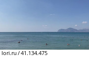 Люди купаются в море. Крым, бухта Провато. Вид на Карадаг. Центральный пляж пгт Орджоникидзе (2023 год). Редакционное видео, видеограф Щеголева Ольга / Фотобанк Лори