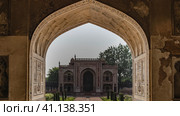 Through the arched opening, a path leading to the ancient mosque in the tomb of Itmad-Ud-Daulah complex is visible. The red sandstone building is decorated with white patterns and ornaments. India. (2022 год). Стоковое фото, фотограф Вера Ивановна Кубарева / Фотобанк Лори