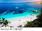 Fteri beach, Cephalonia Kefalonia, Greece. White catamaran yacht in clear blue sea water. Tourists on sandy beach near azure lagoon (2018 год). Стоковое фото, фотограф Igor Tichonow / Фотобанк Лори