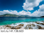 Beautiful cloudscape near Fiskardo, Kefalonia, Ionian islands, Greece. Crystal clear transparent blue turquoise teal Mediterranean sea water in Fiskardo town. White catamaran yacht drift in open sea. Стоковое фото, фотограф Igor Tichonow / Фотобанк Лори