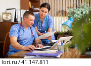 Two focused physicians working with case histories on laptop. Стоковое фото, фотограф Яков Филимонов / Фотобанк Лори