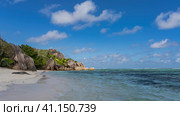 A beautiful beach on a tropical island. Picturesque cliffs with steep smoothed slopes and boulders at the water's edge. Turquoise ocean, white sand, blue sky with clouds. Seychelles. La Digue. (2022 год). Стоковое фото, фотограф Вера Ивановна Кубарева / Фотобанк Лори
