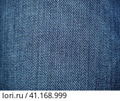 Blue denim. Texture of cotton coarse material. A fragment of a natural rag indigo. Vertical furrows, dark and light threads, individual stitches are noticeable. Стоковое фото, фотограф Юлия Петровская / Фотобанк Лори