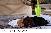 Hands in gloves mix ingredients for the soil of home potted plants, peat, earth, sand, perlite, vermiculite, coconut. A mixture for planting plants in a pot. Layout. Стоковое видео, видеограф Ольга Симонова / Фотобанк Лори