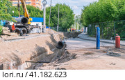 Траншея и замена устаревшего трубопровода. Кислородные и пропановые баллоны для газовой сварки. Кран разгружает трубы теплоснабжения. Строитель регулирует разгрузку труб на улице Шахтерская в городе Пермь. Стоковое фото, фотограф Эдуард Белкин / Фотобанк Лори