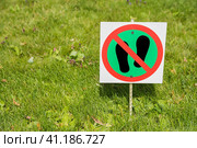 Photo of warning sign, which is meaning that walking on grass is strictly prohibited. The sign is installed in the park on the edge of the lawn area. Фотография предупреждающего знака, который означает, что ходить по траве строго запрещено. Знак установлен в парке на краю газонной зоны. Стоковое фото, фотограф Дмитрий Березнев / Фотобанк Лори