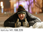 Portrait of middle aged handsome man in the cold winter night in Moscow public park VDNkH. Concept of leisure time and happiness. Close up. man lay down on the snow, he is not cold. Стоковое фото, фотограф YuryKara / Фотобанк Лори