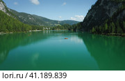 Aerial footage over lake Braies, Pragser Wildsee and mountains, in the background, on a sunny bright. Стоковое фото, фотограф Igor Tichonow / Фотобанк Лори